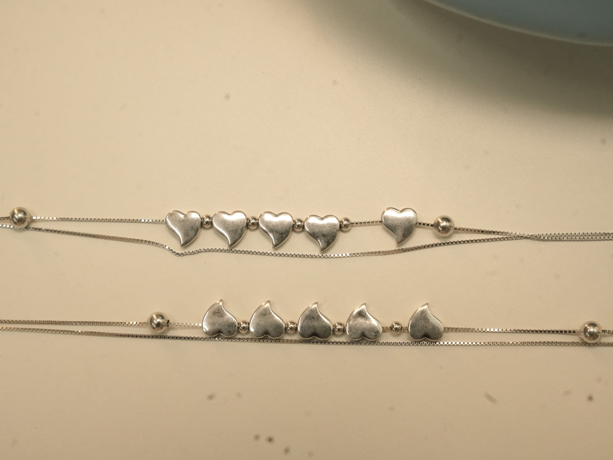 Pair of sterling silver payal, each with five hearts between bead stations on a double strand of box chain.