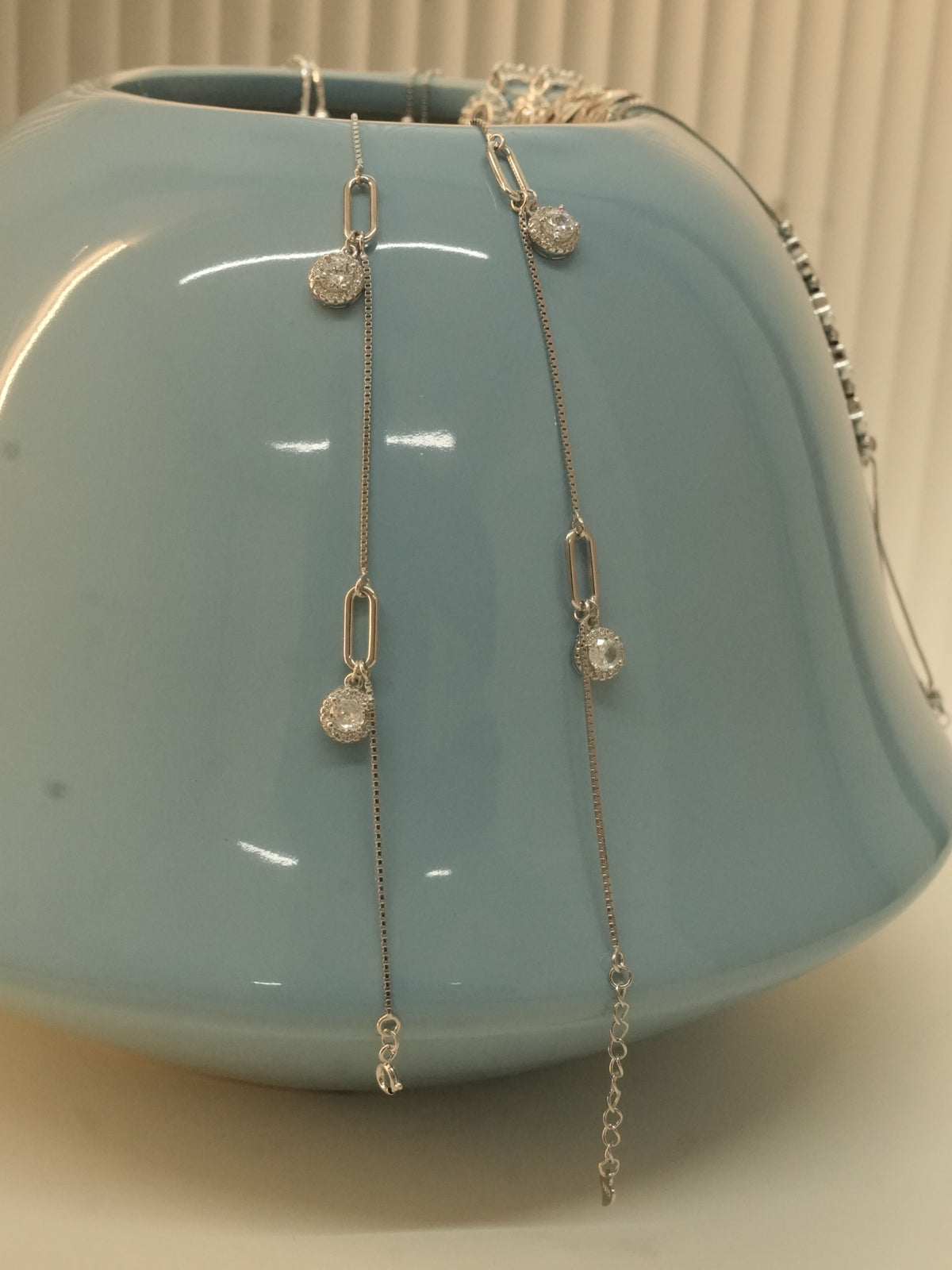 The paperclip link payal draped over a blue ceramic vase.