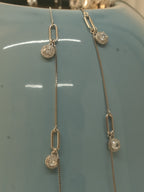 Close view of the paperclip links and American Diamond halo drops against a blue vase.