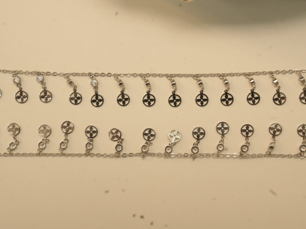 Pair of silver payal with a fringe of flower pierced discs, each hanging from a bezel set American Diamond.