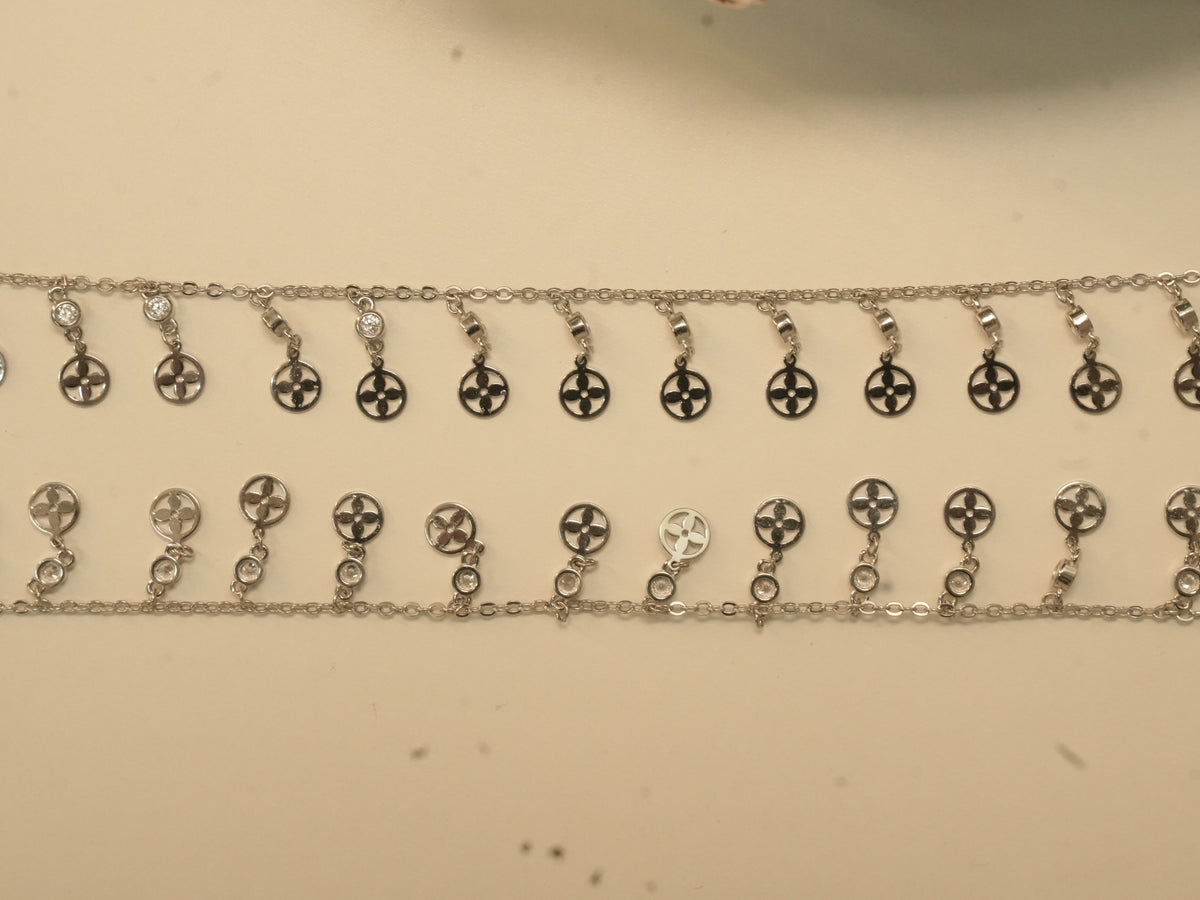 Pair of silver payal with a fringe of flower pierced discs, each hanging from a bezel set American Diamond.