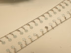 Close view of the round discs pierced with four petal flowers on the silver payal.