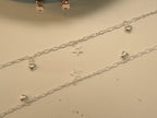 Pair of silver figaro chain payal, each with puffed heart charms and an open star.
