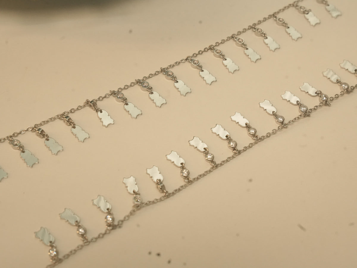 Close view of the scalloped silver tags and bezel set stones on the payal.