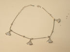 Sterling silver anklet with four fan shaped American Diamond charms, laid in a loop.