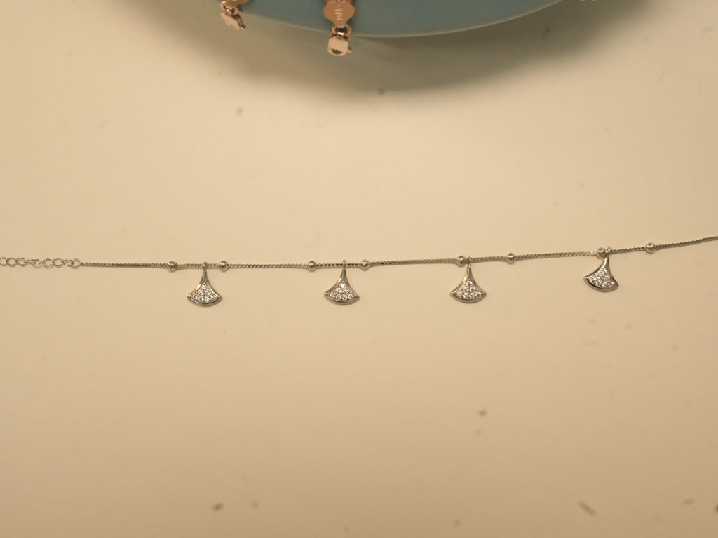 The fan charm anklet laid out straight, showing the four charms.