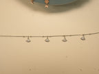 The fan charm anklet laid out straight, showing the four charms.