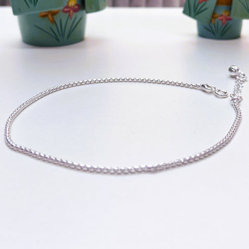 Single sterling silver round box chain anklet with a lobster clasp and extender chain, on a white surface.