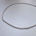 The round box chain anklet laid in a loop to show the even links along its length.