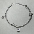 Sterling silver double-strand anklet with a heart charm, a polished ball and an American Diamond inside an open cube, on a pale surface.