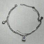 Sterling silver double-strand anklet with a heart charm, a polished ball and an American Diamond inside an open cube, on a pale surface.