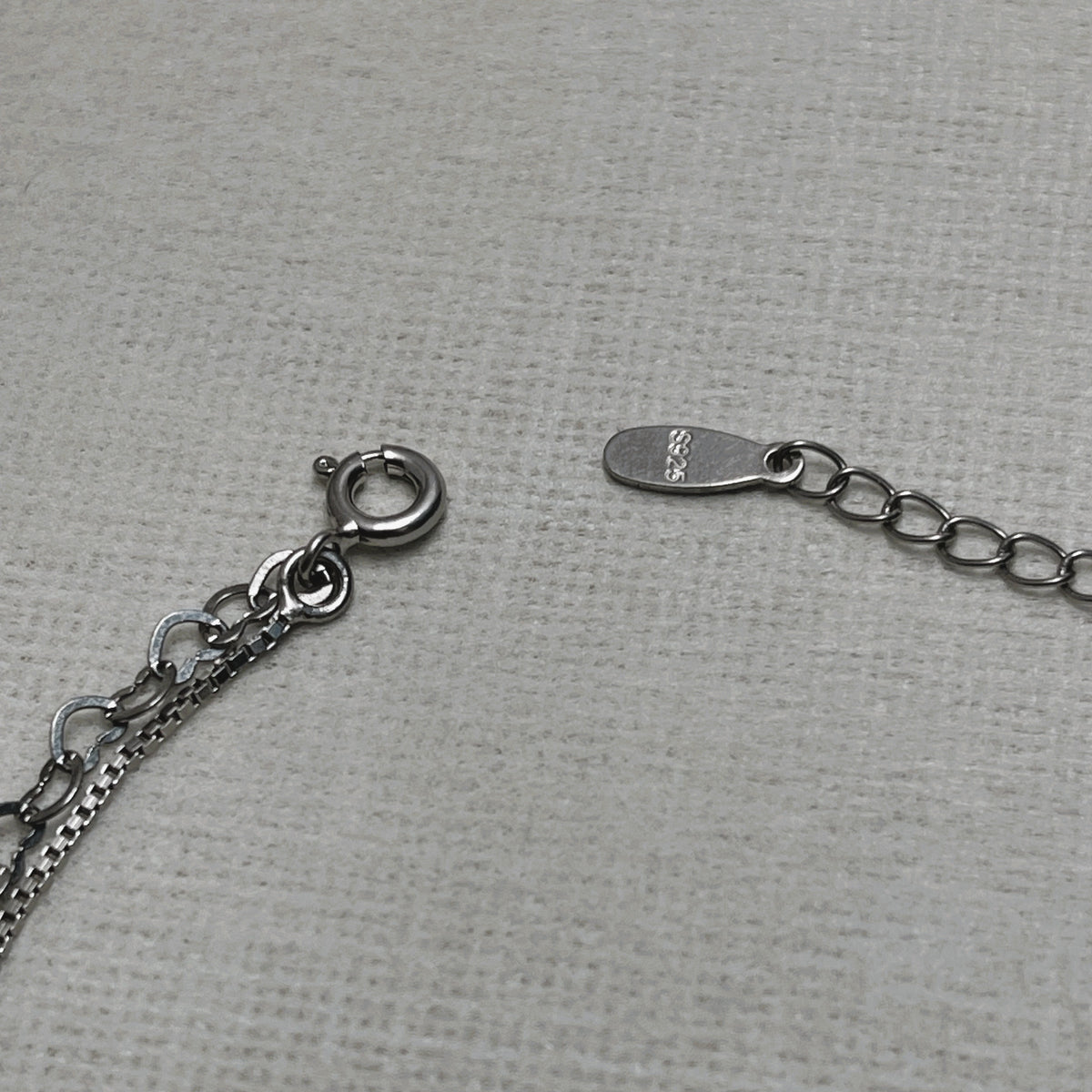 The spring ring clasp and extender chain of the anklet, with the 925 stamped tag.