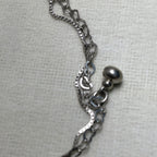 Close-up of the polished silver ball charm where the two chains meet.