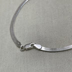 Close-up of the herringbone links and the lobster clasp of the silver anklet.