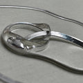 Pair of flat herringbone silver payal: one anklet coiled to show the smooth ribbon of links.