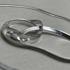 Pair of flat herringbone silver payal: one anklet coiled to show the smooth ribbon of links.