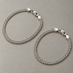 A pair of sterling silver popcorn chain anklets laid side by side.