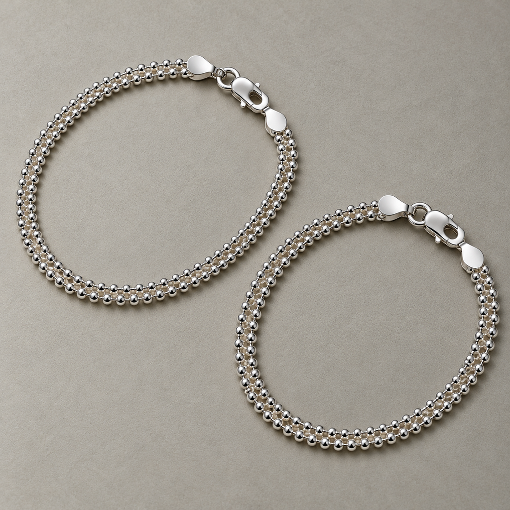 A pair of sterling silver popcorn chain payal laid side by side.