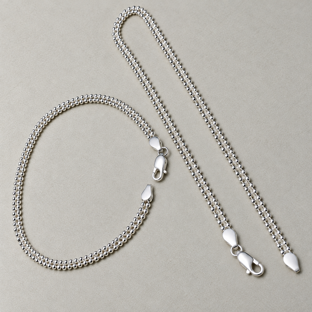 The pair of popcorn chain silver payal, one looped and one laid straight, with both clasps visible.