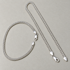 The pair of popcorn chain silver payal, one looped and one laid straight, with both clasps visible.