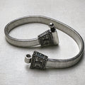 Rajwadi sterling silver payal, a wide flat snake chain with carved oxidised end caps, laid in a loop with the pin clasp open.
