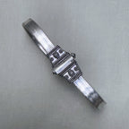 The oxidised carved end cap of the silver anklet, with its beaded borders and leaf motif.