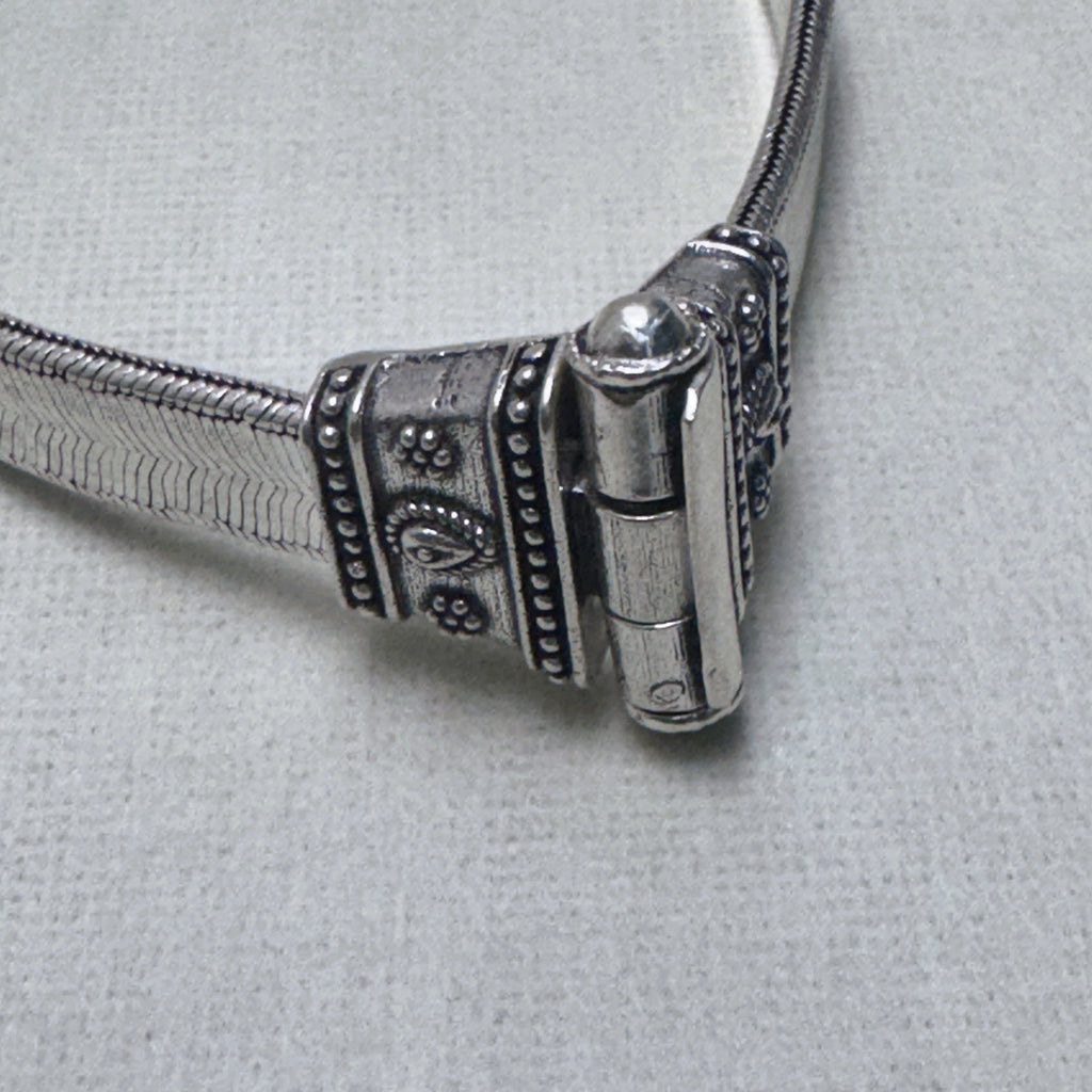 Close-up of the pin clasp of the anklet, the pin seated in its barrel between the two caps.