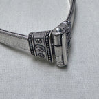 Close-up of the pin clasp of the anklet, the pin seated in its barrel between the two caps.