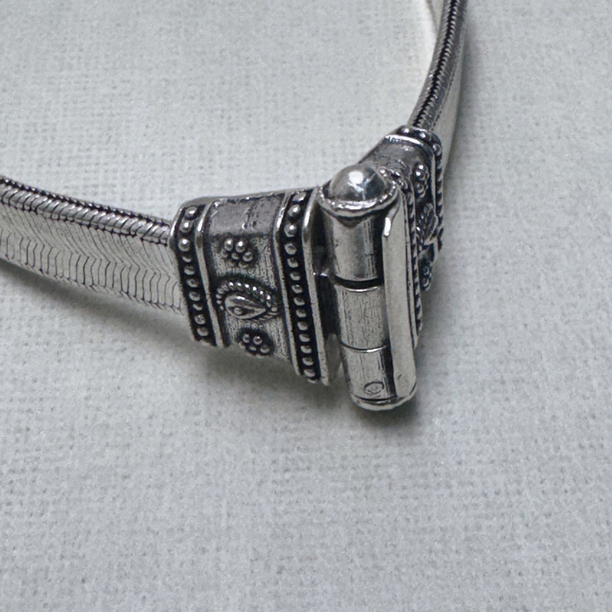 Close-up of the pin clasp of the anklet, the pin seated in its barrel between the two caps.