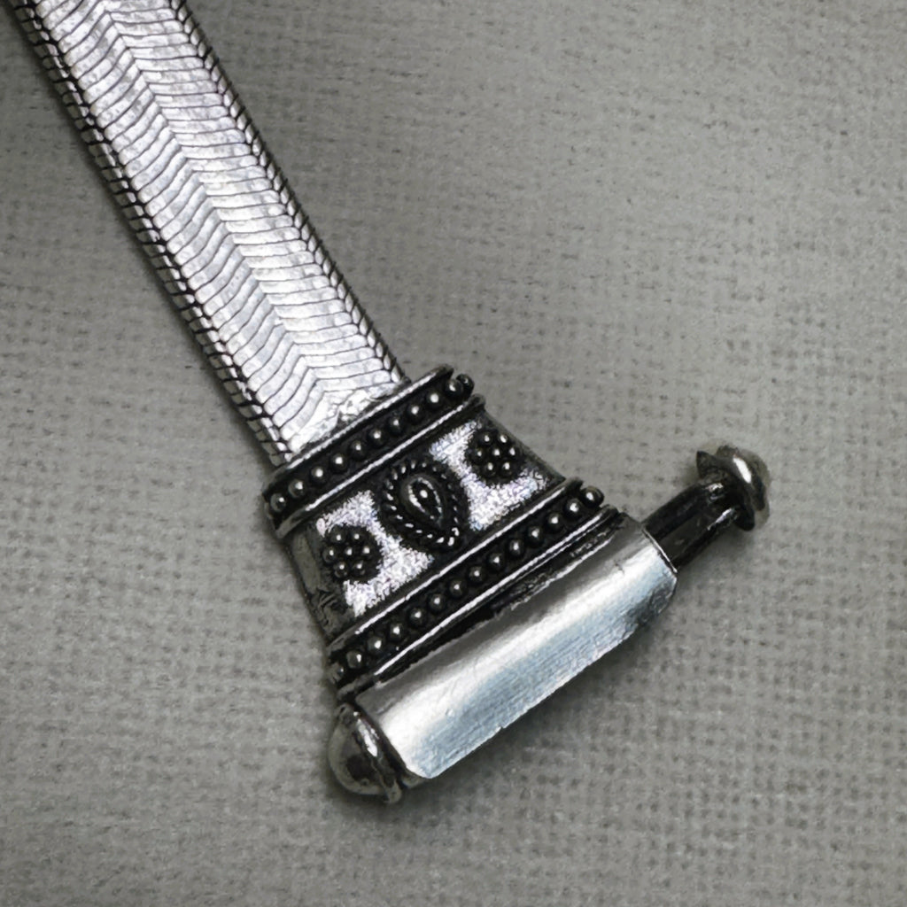 Close-up of one carved oxidised cap with the pin pulled partly out of the barrel.