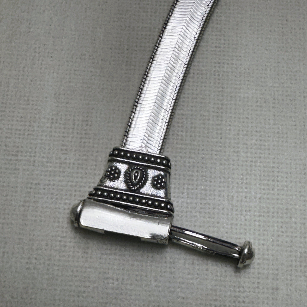 The pin of the clasp drawn out, showing how the bar slides through the barrel.