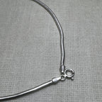 Close-up of the spring ring clasp and the 925 stamped tag on the snake chain anklet.