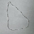 Sterling silver snake chain anklet with small polished bead stations, laid in a loop with its spring ring clasp.