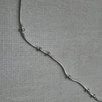 Close-up of the snake chain and the evenly spaced silver beads of the anklet.