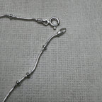The spring ring clasp and end tag of the bead station silver anklet.