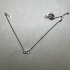 A pair of love knot American Diamond silver payal, one laid out and one gathered beside it.