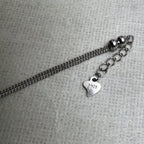 The extender chain, polished beads and heart tag at the clasp end of the love knot anklet.