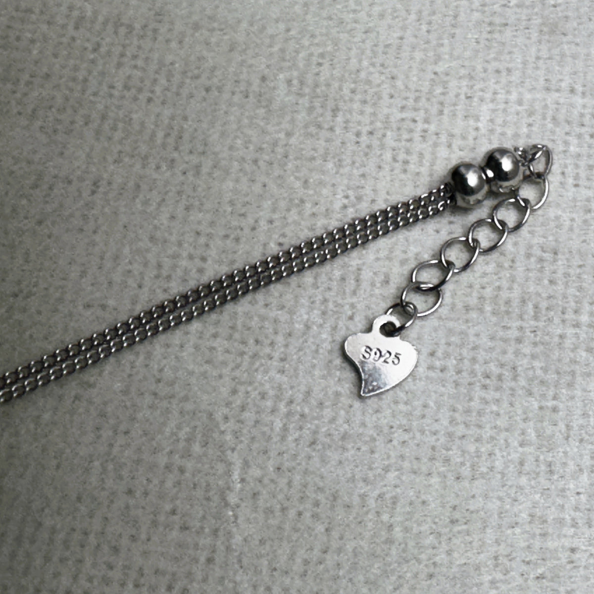 The extender chain, polished beads and heart tag at the clasp end of the love knot anklet.