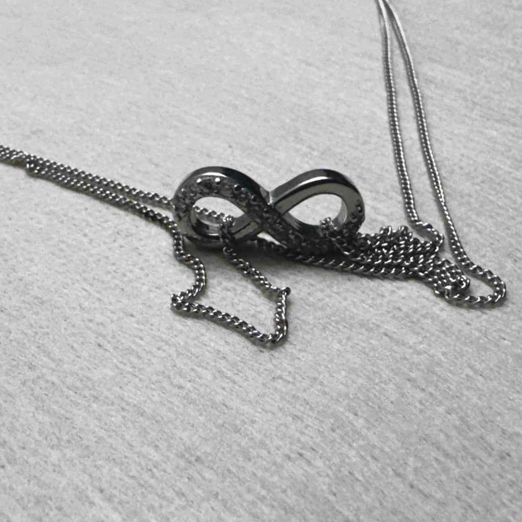 The love knot of the anklet resting on its gathered double curb chain.