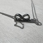 The love knot of the anklet resting on its gathered double curb chain.