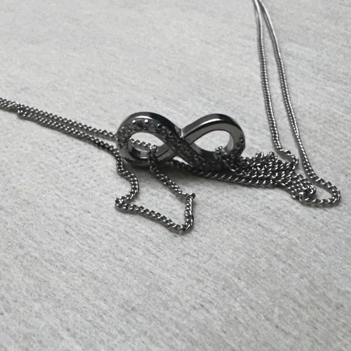 The love knot of the anklet resting on its gathered double curb chain.