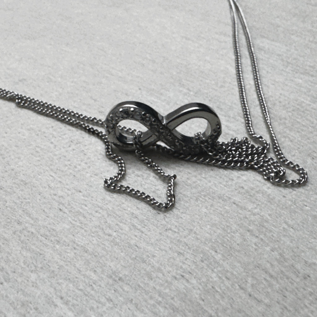 The love knot of one payal resting on its gathered double curb chain.