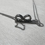 The love knot of one payal resting on its gathered double curb chain.