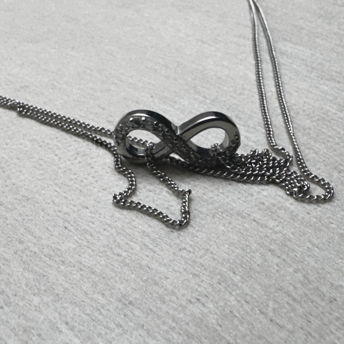 The love knot of one payal resting on its gathered double curb chain.