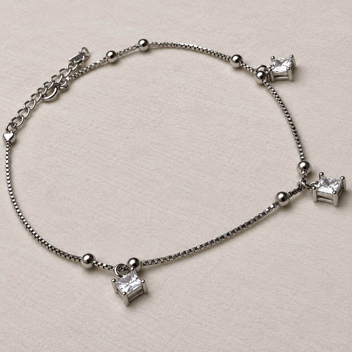 The anklet laid out to show the three square American Diamond drops and the extender chain.