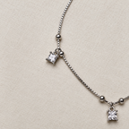 Close-up of two princess-cut American Diamond drops in claw settings on the beaded box chain.