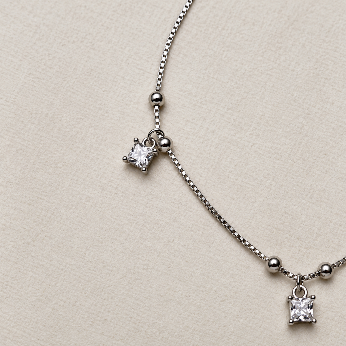 Close-up of two princess-cut American Diamond drops in claw settings on the beaded box chain.