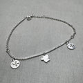 Sterling silver double rolo chain anklet with two emoji face charms and a cat charm, laid in a loop.
