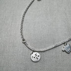 Close-up of the kissing emoji face charm and the cat charm on the silver anklet.