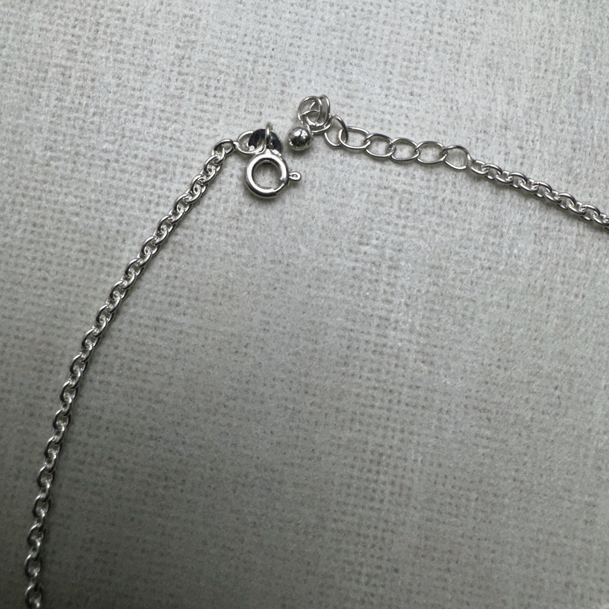 The spring ring clasp and extender chain of the emoji charm silver anklet.